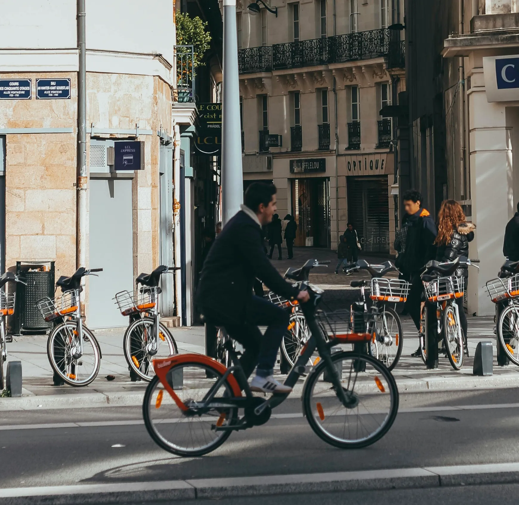 A man in a suit riding a bike down a street.